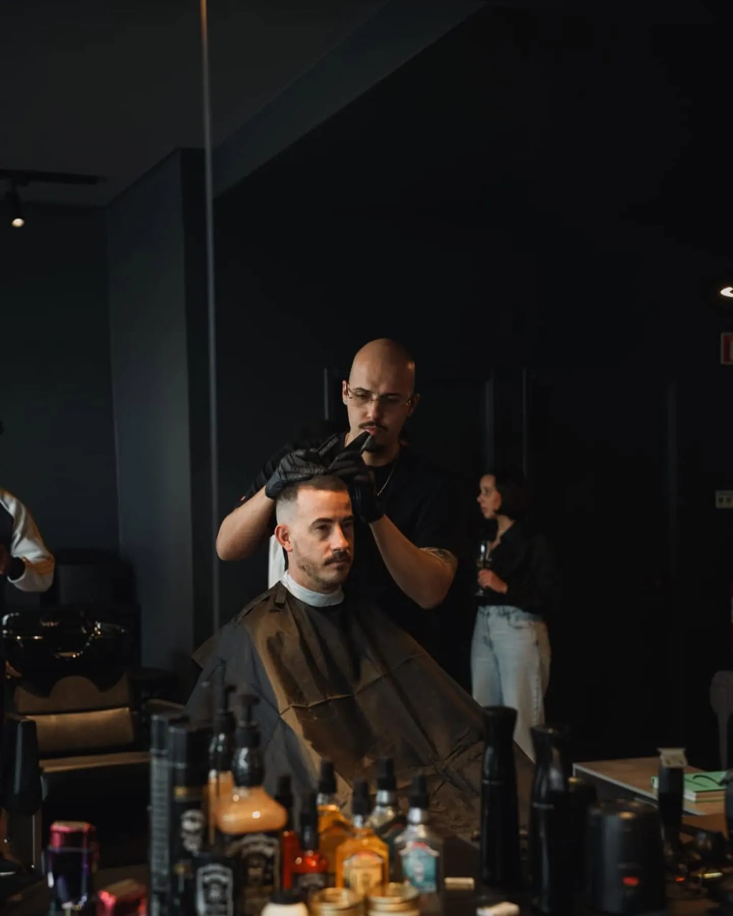 Barbeiro a cortar o cabelo de um cliente em frente ao espelho