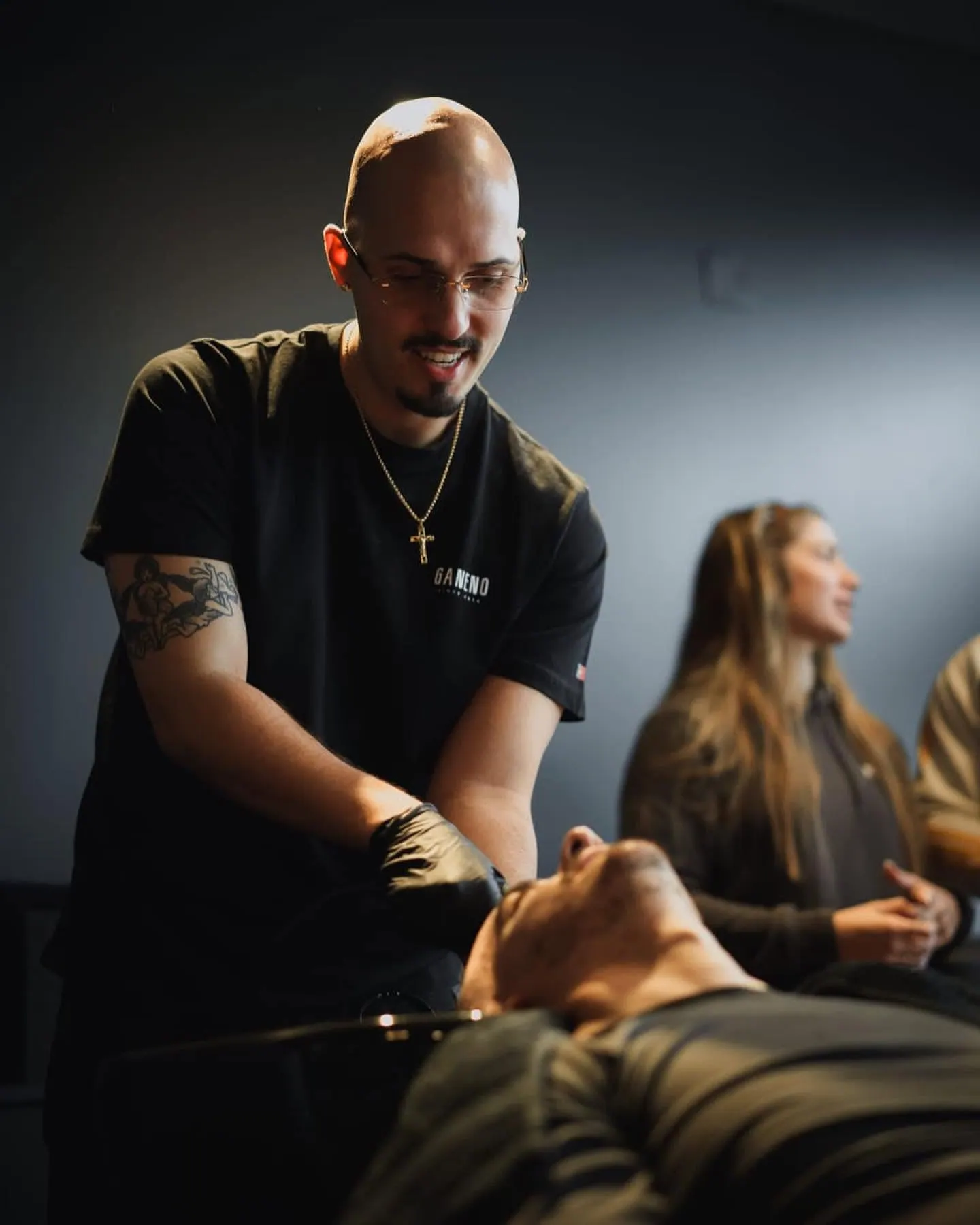 Barbeiro da Ganeno a tratar da barba de um cliente deitado