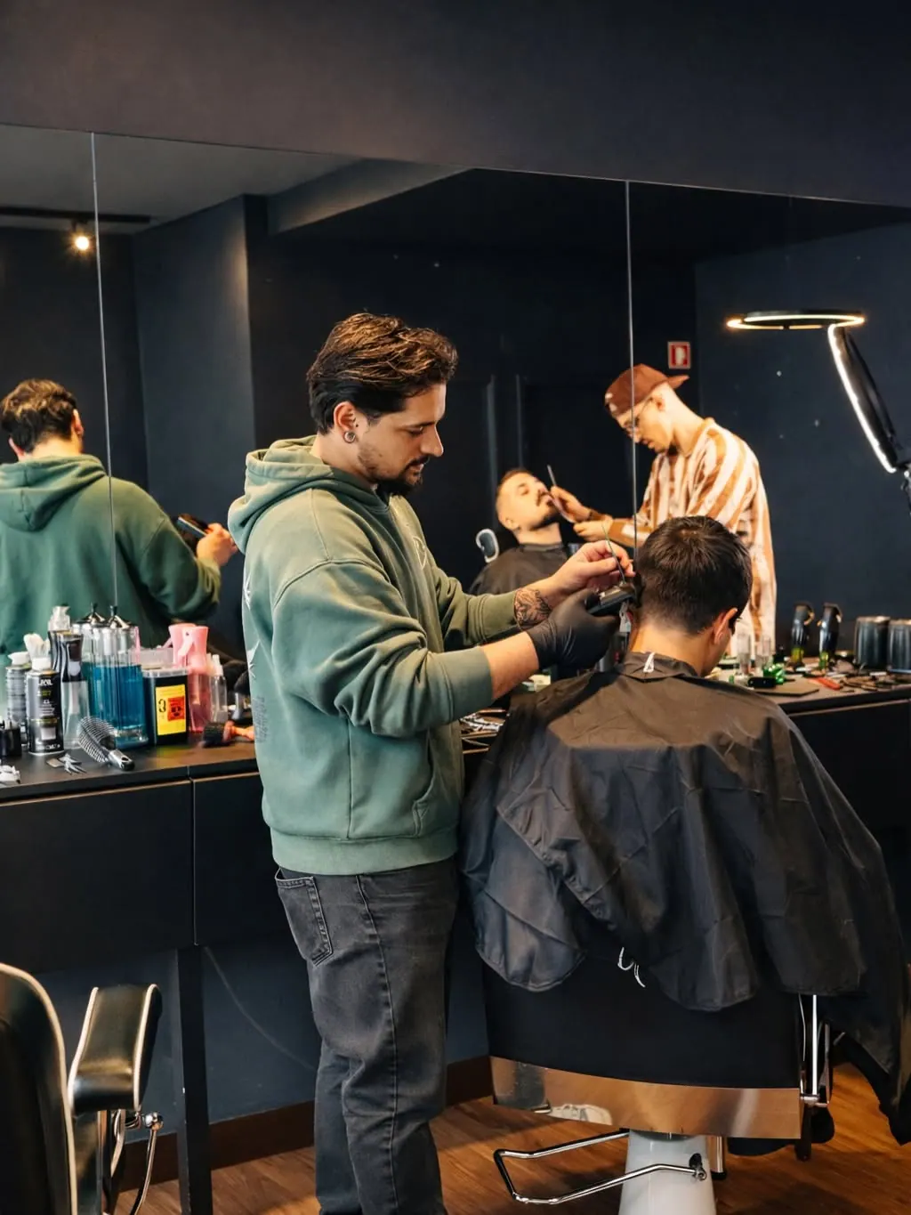 Barbeiro de camisola verde a cortar o cabelo de um cliente